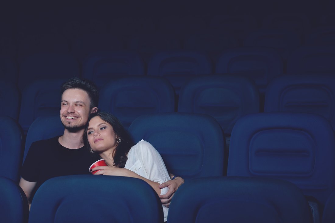 Młoda para przytulona ogląda film na sali kinowej