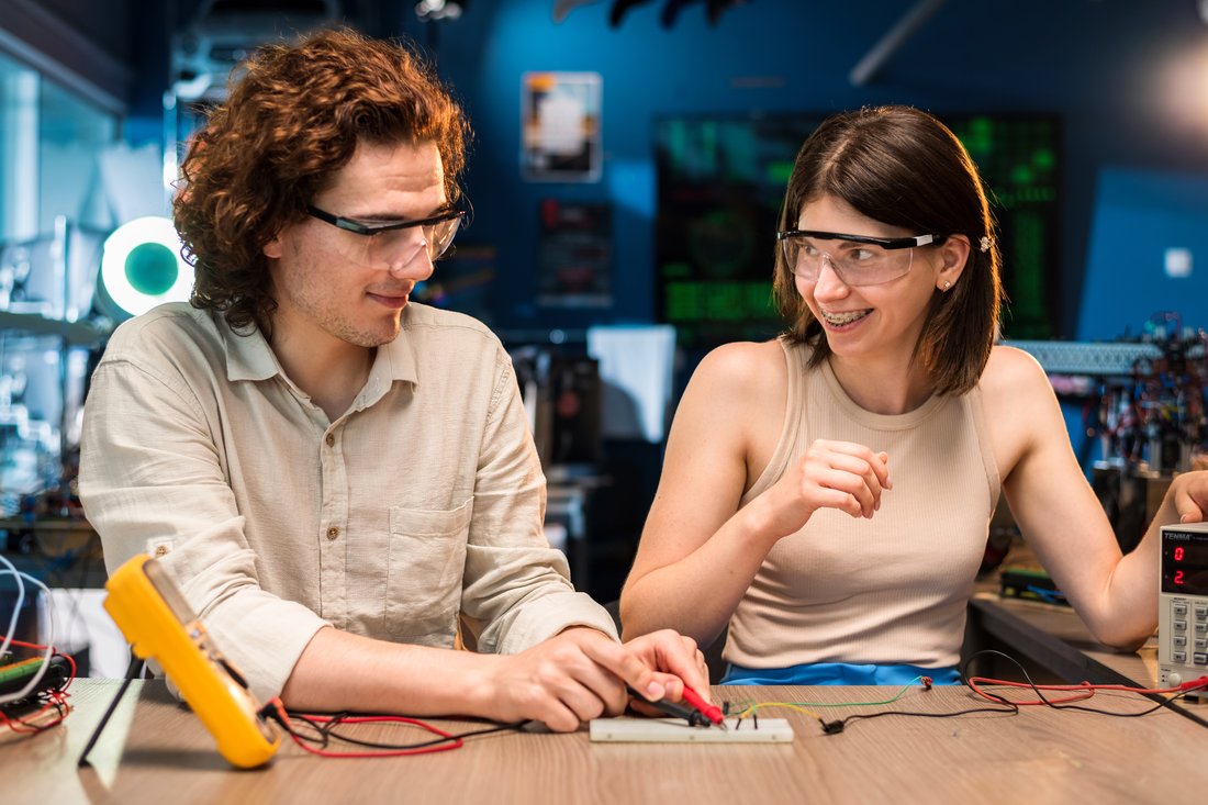 Student i studentka w okularach ochronnych wykonują pomiary elektroniczne w laboratorium